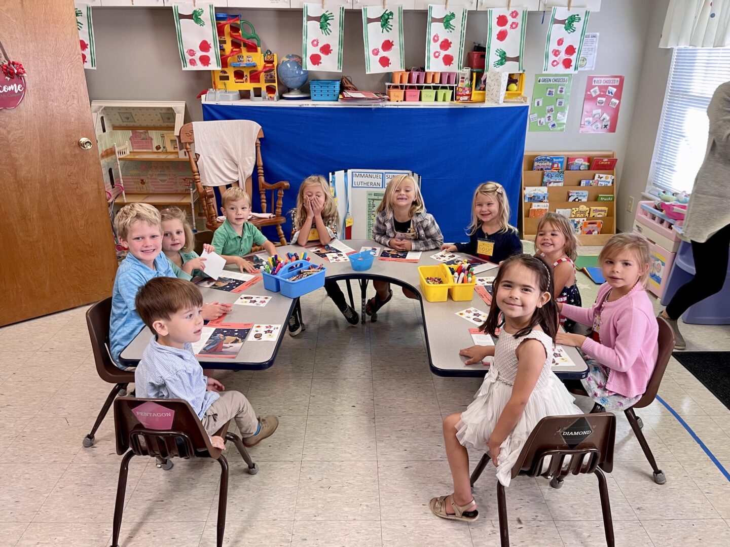 A group of children sitting at a table in a classroom.
