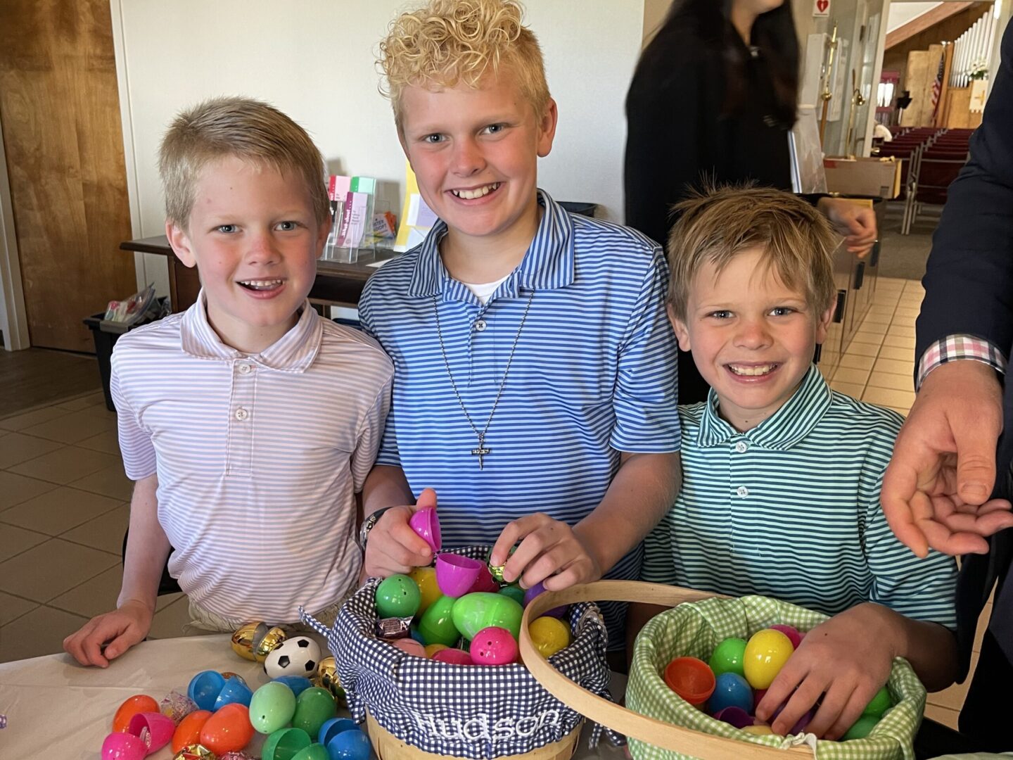 A group of boys are posing in front of a table full of easter eggs.