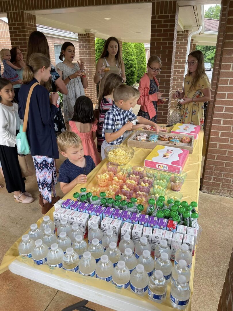 A group of children standing around a table with drinks.